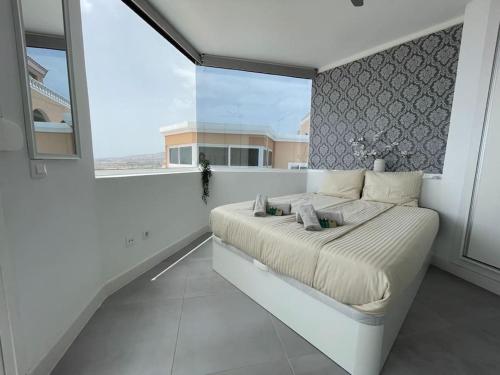 a white bedroom with a bed and a large window at Sunset Terrace Ocean View in Adeje
