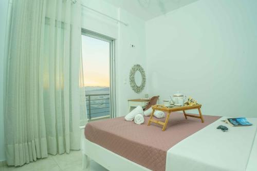 a white bedroom with a bed and a window at Cocoscape Suite, seaside & 270° open view in Kalamaki