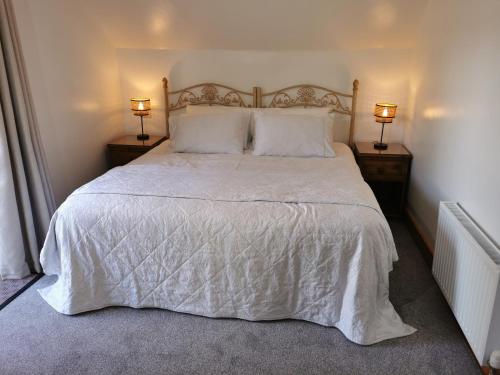 a bedroom with a large white bed with two lamps at The Sanctuary at Boningale Manor in Wolverhampton