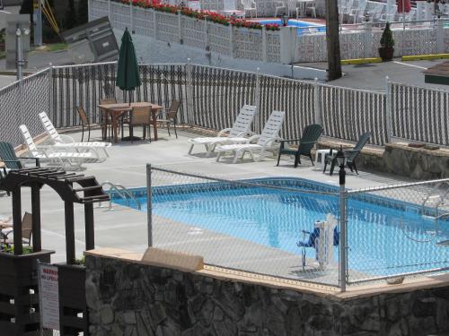 a swimming pool with lounge chairs and a table at The Lake George Inn in Lake George