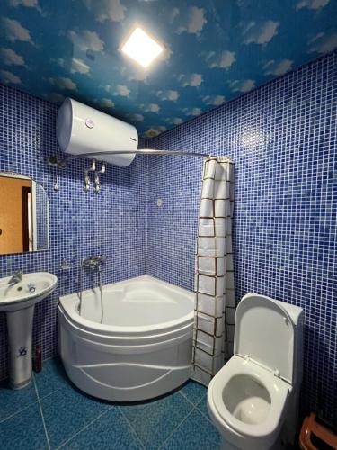 een blauw betegelde badkamer met een toilet en een wastafel bij Major Hotel in Fergana