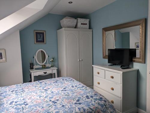 Schlafzimmer mit einem Bett, einer Kommode und einem Spiegel in der Unterkunft Village life- Private suite - Living Room, Bedroom and Bathroom in Newtown Saint Boswells