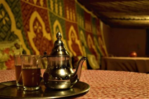 a tea kettle and a glass of tea on a table at La Kasbah du Jardin in Aït Ben Haddou