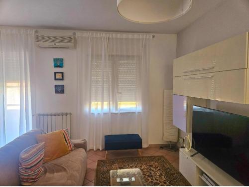 uma sala de estar com um sofá e uma televisão de ecrã plano em Enea residence em Pozzuoli
