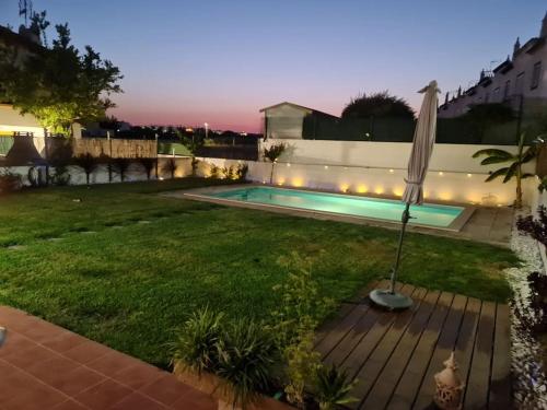a backyard with a swimming pool and an umbrella at Vila T2 Algarve piscina privada in Vila Nova De Cacela