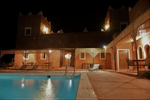 a swimming pool in front of a building at night at La Kasbah du Jardin in Aït Ben Haddou
