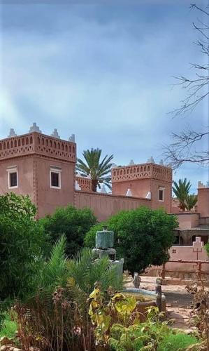 a large brick building with a palm tree in the background at La Kasbah du Jardin in Aït Ben Haddou