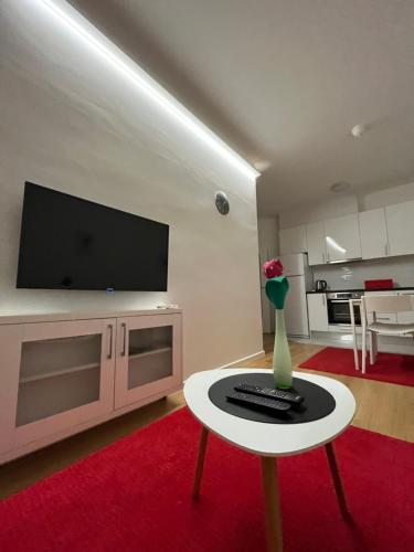 a living room with a television and a vase of flowers on a table at Apartman Luca in Široki Brijeg