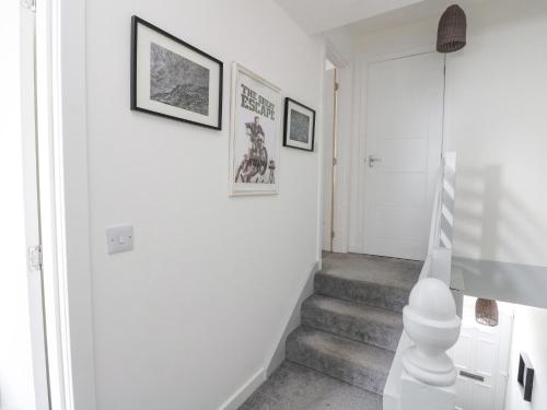 a white hallway with stairs and pictures on the wall at Anchor Cottage in Elgin