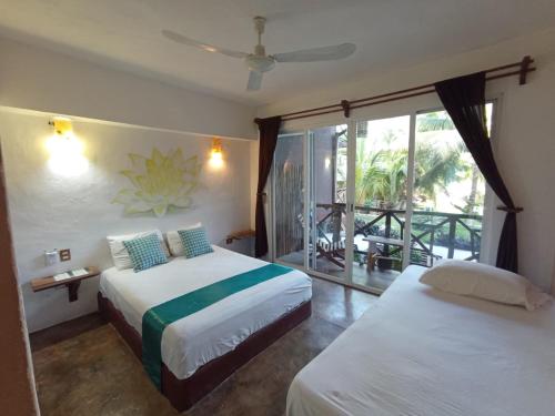 a hotel room with two beds and a balcony at Eco Hotel Casa Corazón Bacalar in Bacalar