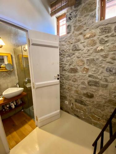 a bathroom with a door and a stone wall at Monastery View House in Mandrakion