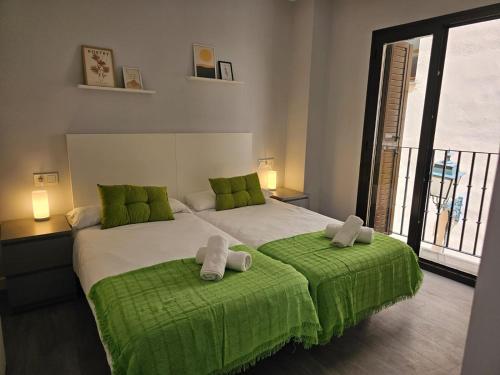 1 dormitorio con 1 cama grande con almohadas verdes en IMEDA Apartamentos Piedra Santa, en Granada