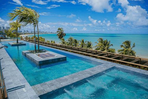 a swimming pool with a view of the ocean at Unity #325 - Conforto em Cabo Branco por Carpediem in Penha