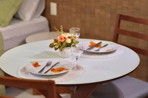 a white table with plates and glasses and flowers on it at Unity #325 - Conforto em Cabo Branco por Carpediem in Penha