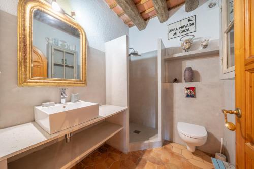 een badkamer met een wastafel, een toilet en een spiegel bij Villa Romana in L'Escala