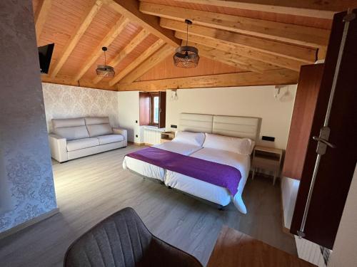 Un dormitorio con una cama grande y un sofá. en Casona de ventas, en Portomarín