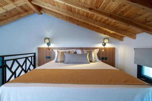 a bedroom with a large bed with wooden ceilings at Arroyo Suites Kalamitsi in Kalamitsi