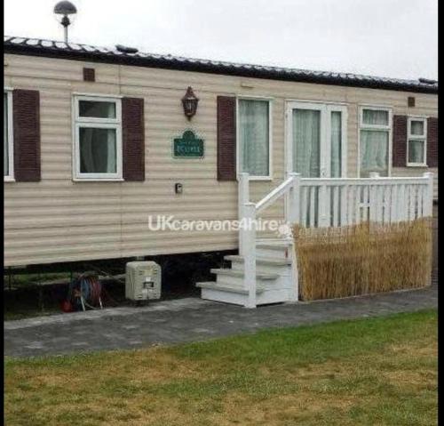a mobile home with a porch and stairs in a yard at Presthaven Sands in Prestatyn