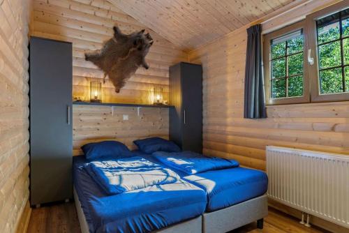 two beds in a room with wooden walls and windows at De Blije Wereld in Otterlo