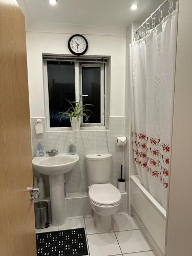 a bathroom with a toilet and a sink and a clock at Dreams Home in Northfleet