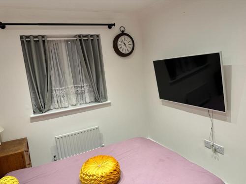 een woonkamer met een tafel met een televisie en een klok bij Dreams Home in Northfleet