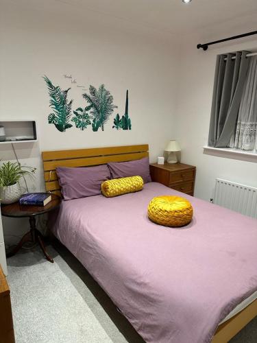 a bedroom with a purple bed with a yellow pillow on it at Dreams Home in Northfleet