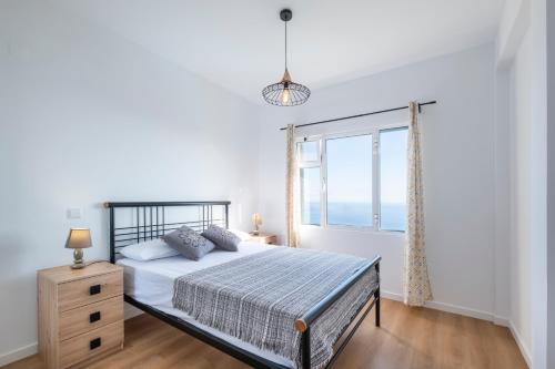 a white bedroom with a bed and a window at Tucha's Apartement in Funchal