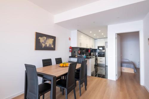 a kitchen and dining room with a wooden table and black chairs at Tucha's Apartement in Funchal