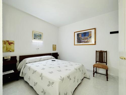 a white bedroom with a bed and a chair at Ambient CostaBravaSi in Platja d'Aro