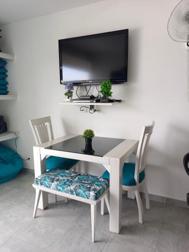 a white table and chairs with a tv on a wall at AQUAVALE - Apartamento Vacacional en Girardot in Girardot