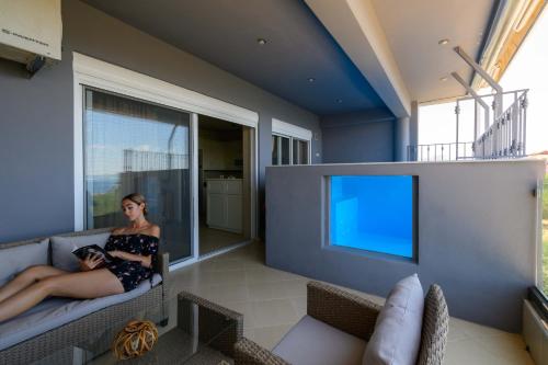 a woman sitting on a couch in a living room at Grand Suites with Private Pools in Kalamata