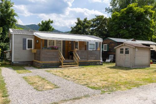 a tiny house with a porch and a shed at Grand Mobil Home 6 personnes climatisé avec 3 chambres et 2 salles de bains à Munster en Alsace in Munster