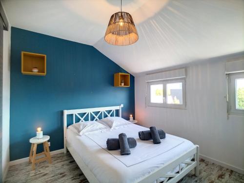 a bedroom with a white bed with a blue wall at L'écume in Granville