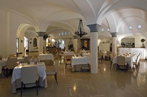 un ristorante con tavoli e sedie bianchi e un lampadario a braccio di Hotel Residence ad Amalfi