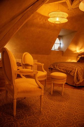a bedroom with a bed and two chairs and a table at La Maison d'Horbé in La Perrière