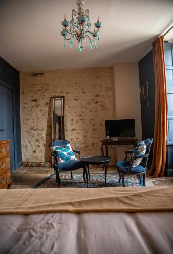 a living room with chairs and a table and a chandelier at La Maison d'Horbé in La Perrière