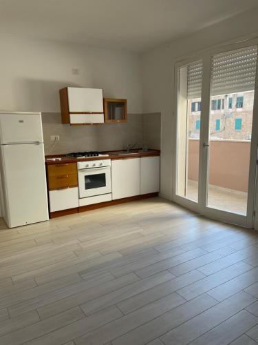 a kitchen with white appliances and a wooden floor at Cravellet 67 in Alghero