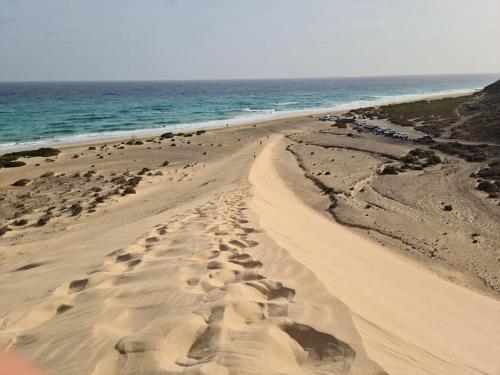 a sandy beach with footprints in the sand and the ocean at Premium Residence Isabel in Costa Calma