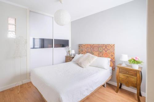 セビリアにあるapartamento Castillaの白いベッドルーム(白いベッド1台、木製テーブル付)