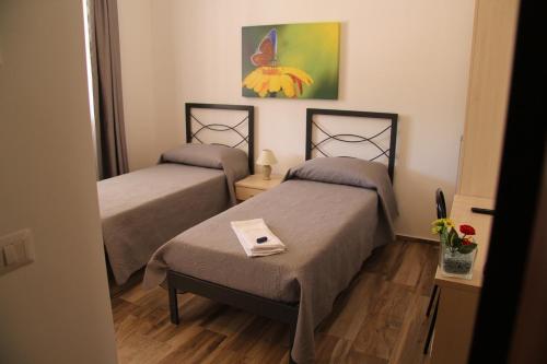 een kamer met twee bedden en een schilderij aan de muur bij Miramurgia B&B in Gravina in Puglia