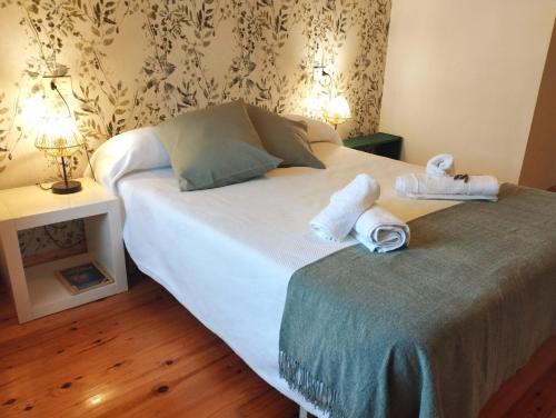 una camera da letto con un letto con asciugamani e due lampade di Casa Aldea de Abaixo a Lugo