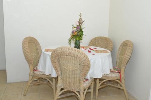 un tavolo con quattro sedie e un vaso di fiori sopra di Hilltop View Guesthouse a Castries