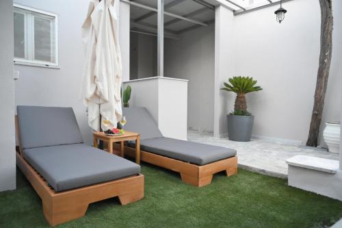 two chairs and a table in a patio with grass at Villa Val-Gio in Ermoupoli