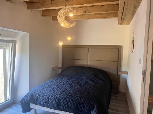 um quarto com uma cama e um lustre em Gîte du ptit château 