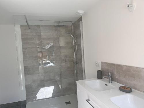 uma casa de banho branca com um chuveiro e um lavatório. em Gîte du ptit château 