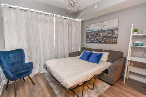 Habitación pequeña con sofá y silla azul. en King & Queen Bed, Pool, Firepit, Fully Stocked en Innisfil