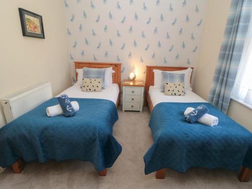 two twin beds in a room with blue blankets and pillows at The Old School House in Scarborough