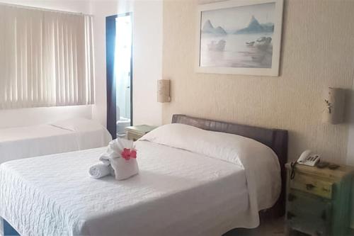 a bedroom with a white bed with a stuffed animal on it at Pousada do Albatroz in Cabo Frio