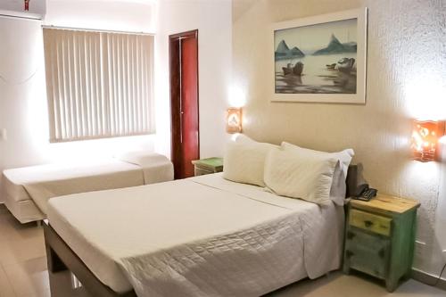 a small bedroom with a bed and a window at Pousada do Albatroz in Cabo Frio