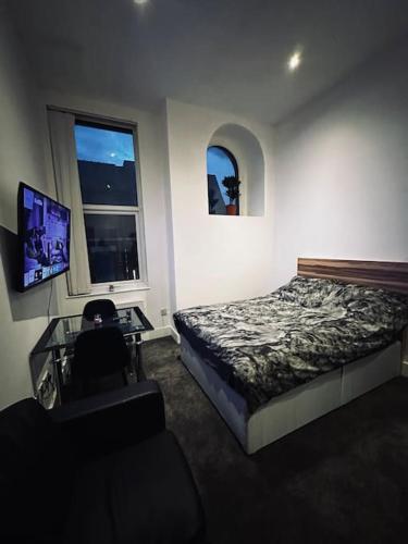 a bedroom with a bed and a desk and a television at 5 STAR LUXURY STUDIO APARTMENT, BIG SMART TV, WiFI, LIVERPOOL CITY CENTRE, EASY ACCESS LOCK BOX ENTRY! in Liverpool